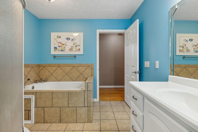 bathroom with baseboards, tile patterned floors, a textured ceiling, vanity, and a bath