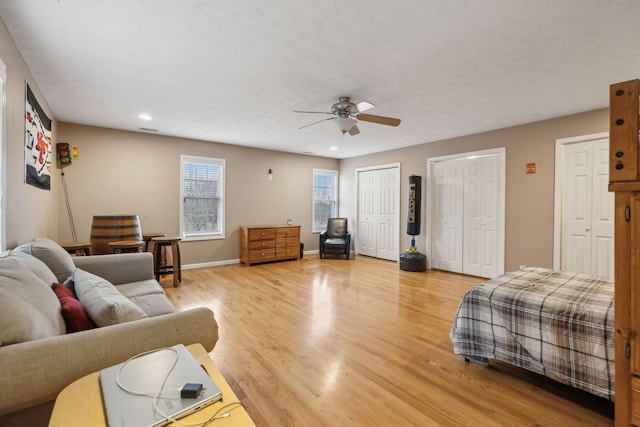 bedroom featuring ceiling fan, recessed lighting, baseboards, light wood-style floors, and two closets