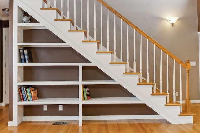 stairway with built in shelves and wood finished floors