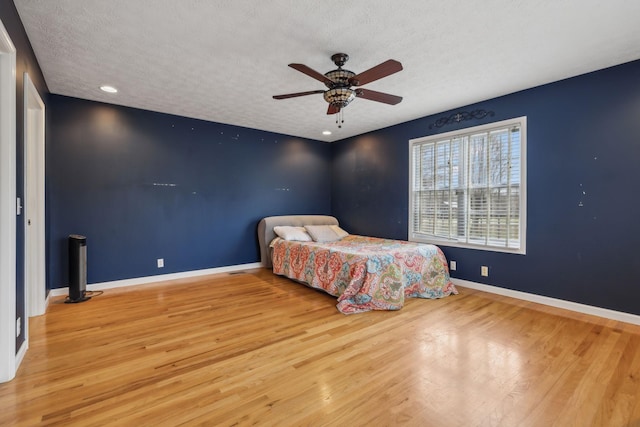 bedroom with a textured ceiling, baseboards, and wood finished floors