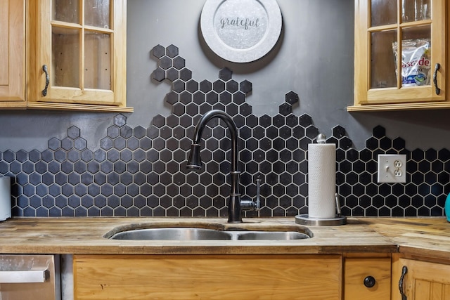 kitchen featuring glass insert cabinets, decorative backsplash, wooden counters, and a sink