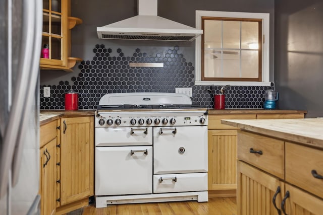 kitchen featuring light wood-type flooring, refrigerator, backsplash, and wall chimney range hood