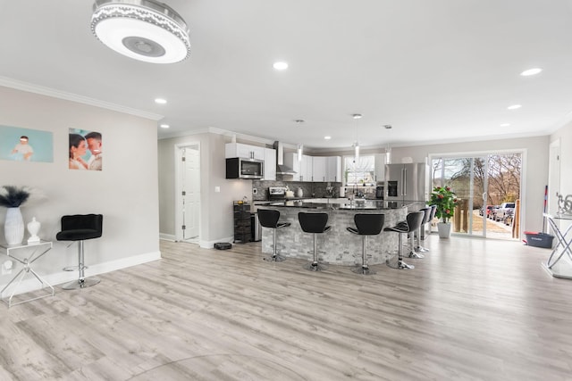 kitchen featuring a breakfast bar, stainless steel appliances, light wood-style flooring, decorative backsplash, and baseboards