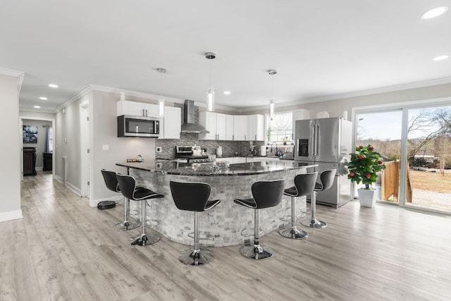 kitchen featuring appliances with stainless steel finishes, a breakfast bar area, backsplash, and wall chimney exhaust hood