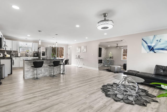 living room with light wood-type flooring, baseboards, a fireplace, and ornamental molding