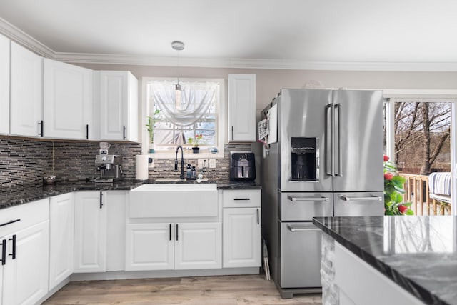 kitchen with a wealth of natural light, stainless steel fridge, a sink, and backsplash