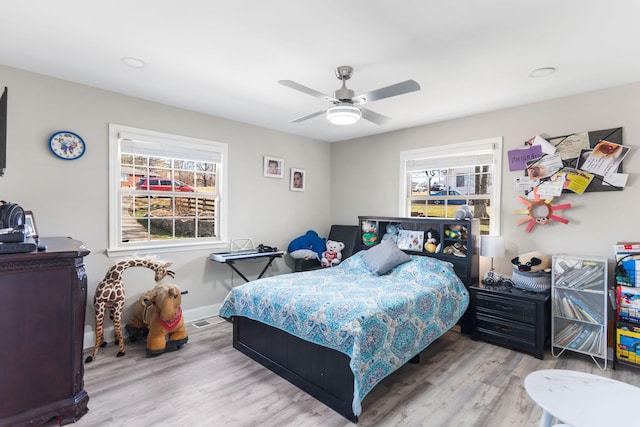 bedroom with a ceiling fan, multiple windows, visible vents, and wood finished floors