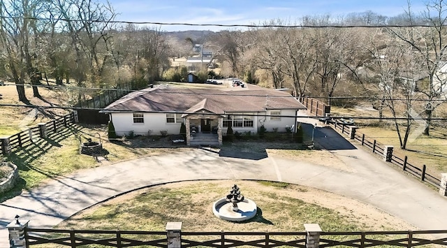 view of front of house featuring a fenced front yard, driveway, a fire pit, and a front lawn