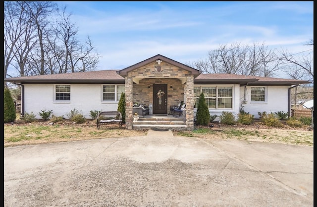 single story home featuring stone siding, a porch, and brick siding