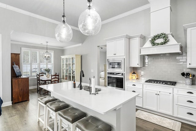 kitchen with stainless steel appliances, wood finished floors, a sink, and custom range hood