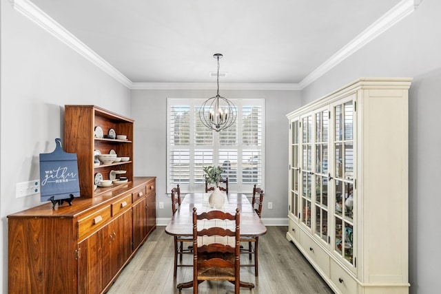 dining space featuring a notable chandelier, crown molding, visible vents, and light wood-style floors