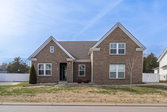 traditional-style home with brick siding, a front lawn, and a gate