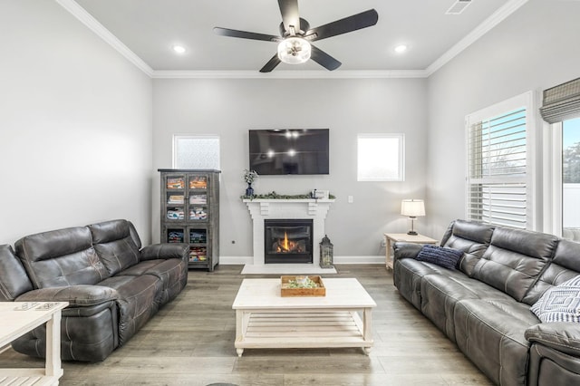 living area with plenty of natural light, crown molding, and light wood finished floors