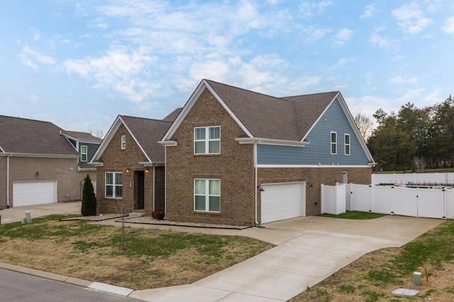 view of front facade with an attached garage, brick siding, fence, driveway, and a gate