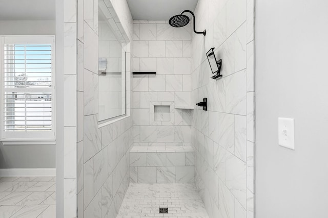 full bathroom with marble finish floor, baseboards, and tiled shower