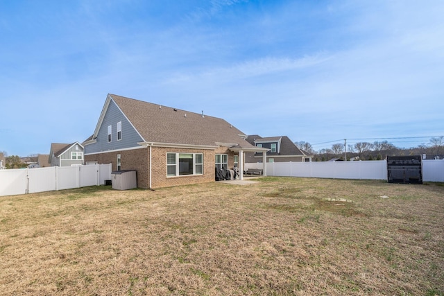 back of house featuring a patio area, brick siding, a yard, and a fenced backyard