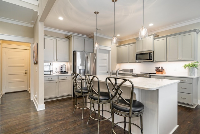 kitchen with appliances with stainless steel finishes, a kitchen breakfast bar, light countertops, gray cabinetry, and a sink