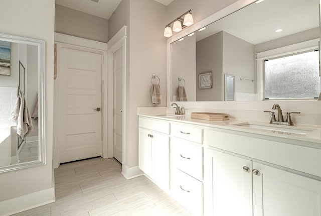 full bathroom featuring double vanity, a sink, and baseboards