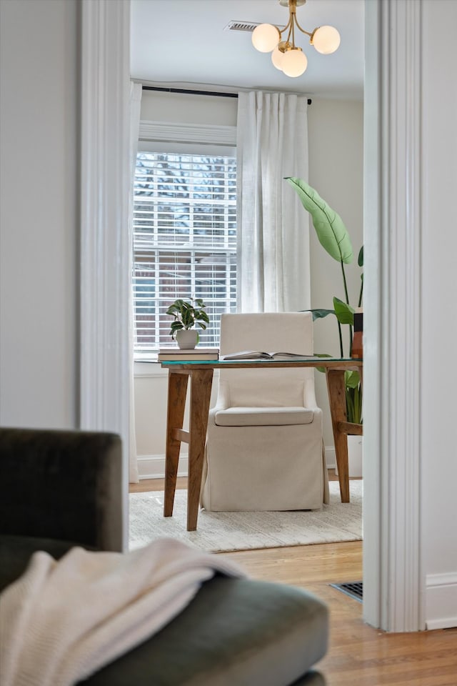 sitting room featuring an inviting chandelier, baseboards, visible vents, and wood finished floors