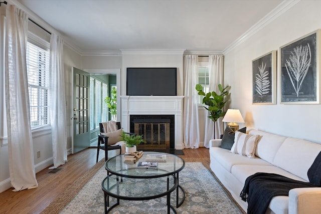 living room featuring a fireplace with flush hearth, visible vents, ornamental molding, and wood finished floors