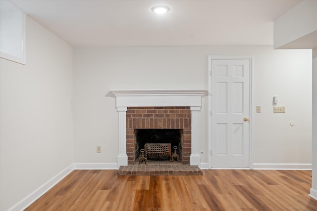 unfurnished living room with light wood finished floors, a fireplace, and baseboards