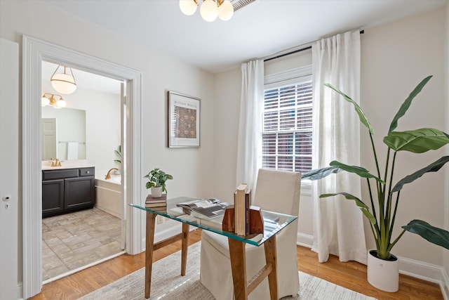 office featuring baseboards, light wood-style floors, and an inviting chandelier