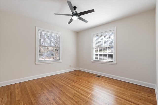 unfurnished room featuring plenty of natural light, visible vents, and baseboards