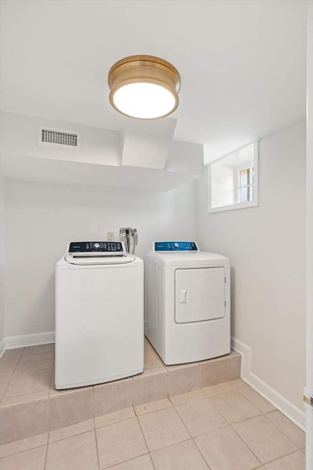 laundry area featuring laundry area, light tile patterned floors, baseboards, visible vents, and washing machine and clothes dryer