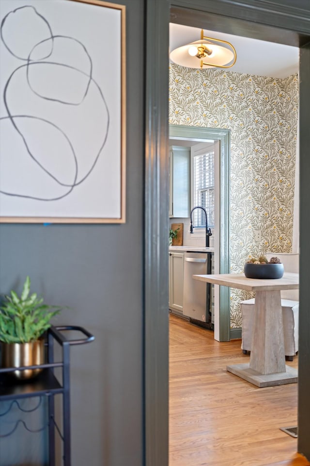 hall featuring light wood-style floors and wallpapered walls