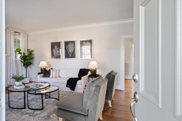 living room featuring ornamental molding, visible vents, baseboards, and wood finished floors