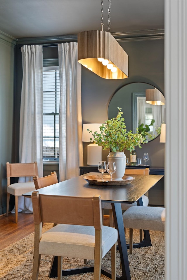 dining area with ornamental molding and wood finished floors