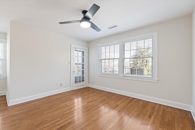 empty room with light wood-type flooring, visible vents, baseboards, and a ceiling fan