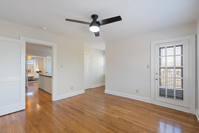 empty room featuring ceiling fan, baseboards, and wood finished floors