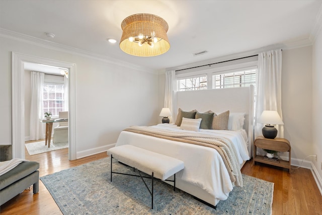 bedroom featuring crown molding, a notable chandelier, visible vents, wood finished floors, and baseboards