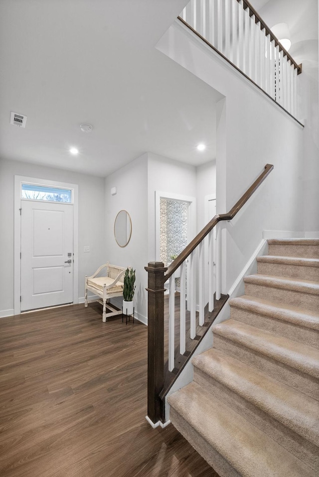 foyer featuring recessed lighting, dark wood-type flooring, visible vents, baseboards, and stairs