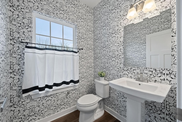 half bath featuring baseboards, toilet, and wood finished floors