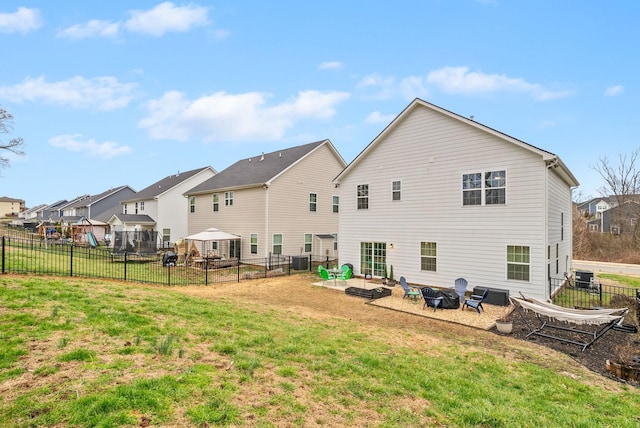 back of house with central air condition unit, fence, a fire pit, and a yard