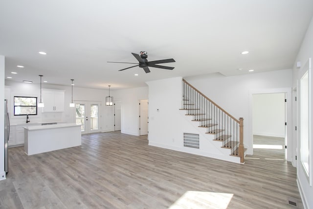 unfurnished living room with light wood-type flooring, visible vents, stairway, and recessed lighting