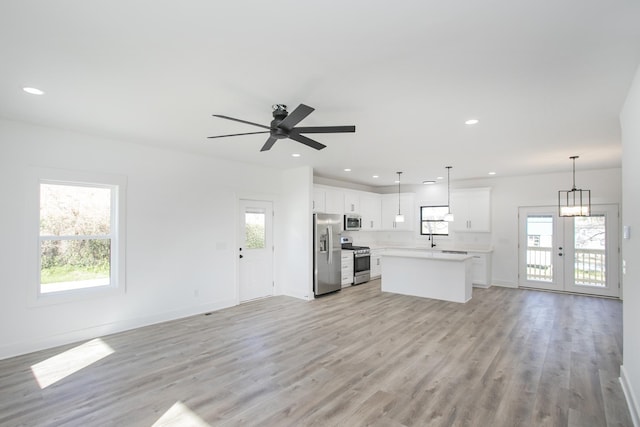 kitchen featuring stainless steel appliances, light countertops, light wood-style flooring, open floor plan, and a kitchen island