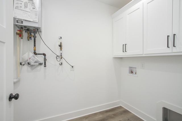 clothes washing area with cabinet space, baseboards, wood finished floors, water heater, and washer hookup