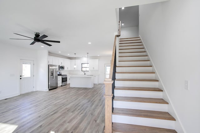 staircase with ceiling fan, baseboards, wood finished floors, and recessed lighting