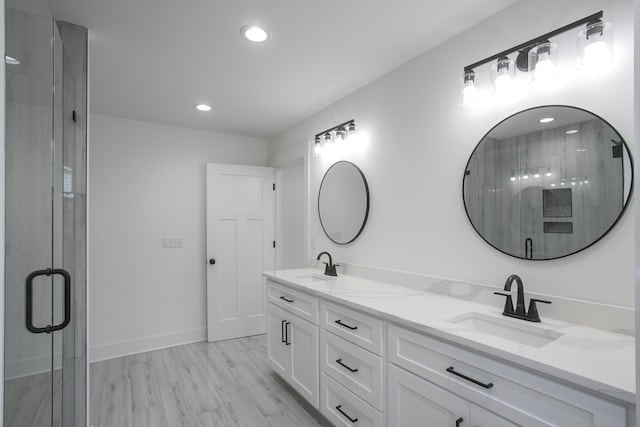 bathroom with double vanity, wood finished floors, a sink, and a shower stall