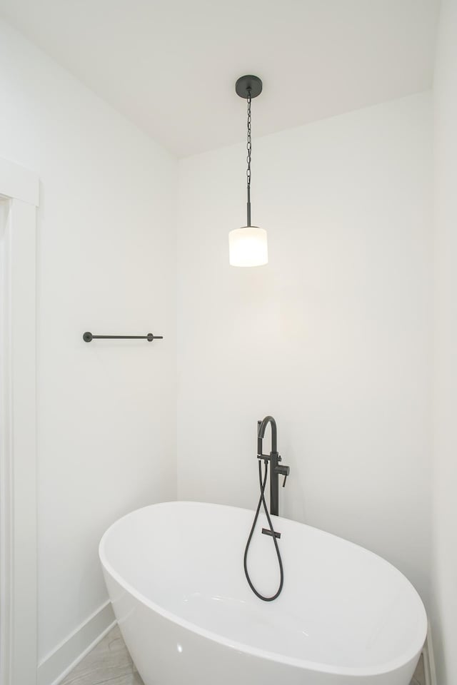 full bathroom featuring a freestanding bath and baseboards