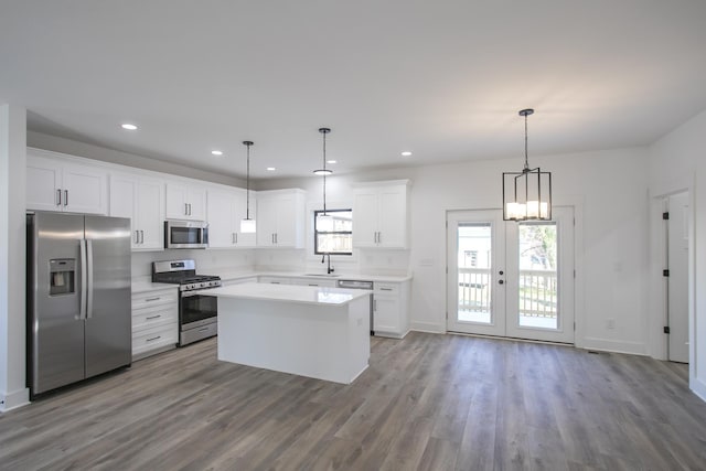 kitchen with stainless steel appliances, dark wood-style flooring, a sink, white cabinetry, and a center island