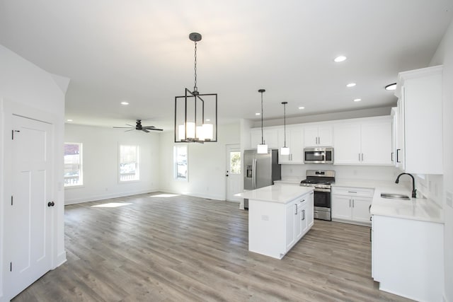 kitchen featuring light wood-style flooring, appliances with stainless steel finishes, open floor plan, a sink, and a kitchen island