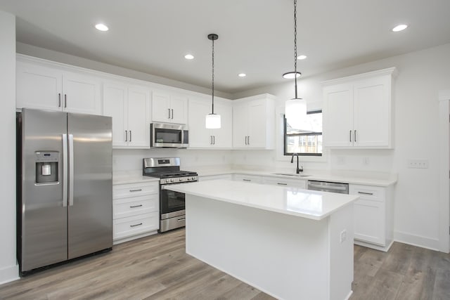 kitchen featuring white cabinets, stainless steel appliances, a sink, and a center island