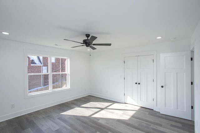 unfurnished bedroom with recessed lighting, wood finished floors, and baseboards