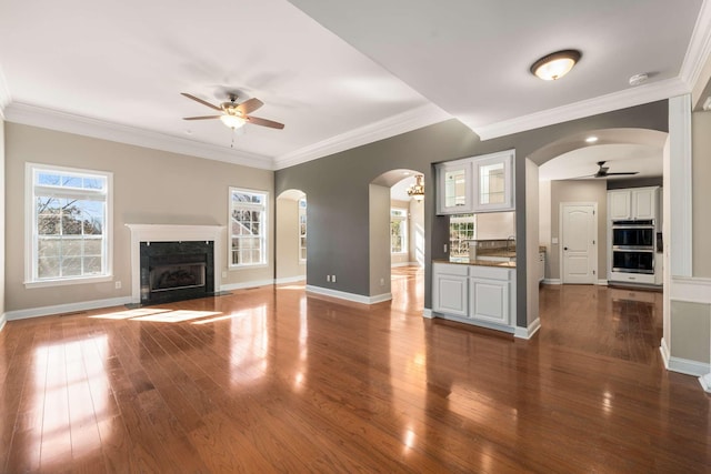 unfurnished living room with ceiling fan, a premium fireplace, baseboards, and dark wood finished floors