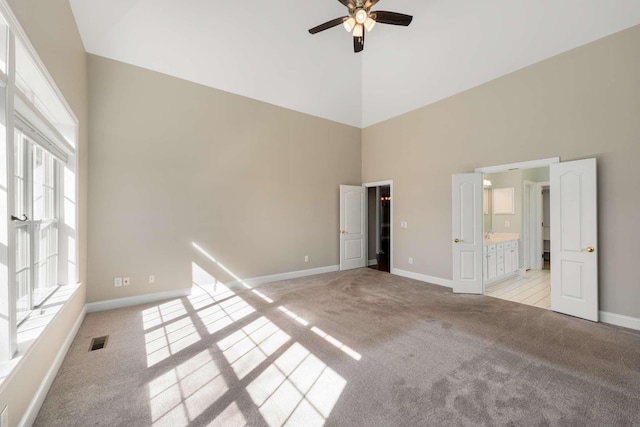 unfurnished bedroom featuring high vaulted ceiling, multiple windows, visible vents, and light colored carpet