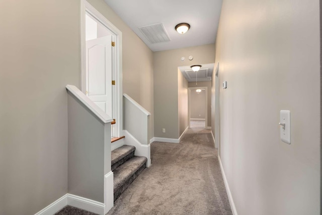 hall featuring attic access, carpet flooring, visible vents, and baseboards